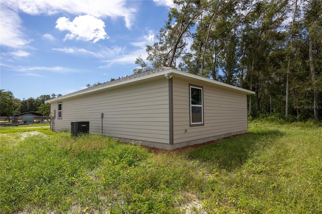 view of side of property with central air condition unit and a lawn