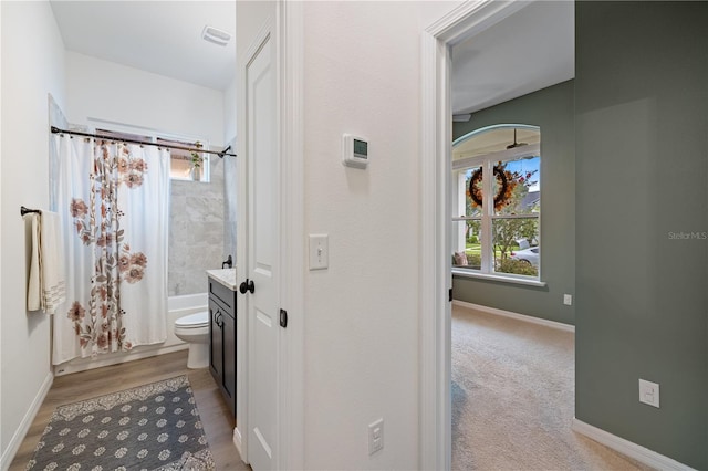 full bathroom with wood-type flooring, vanity, shower / tub combo, and toilet