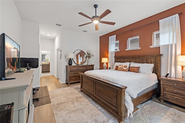 bedroom featuring ceiling fan, connected bathroom, and light hardwood / wood-style floors