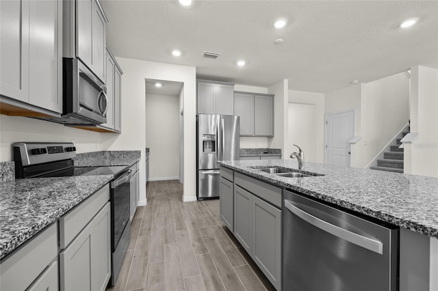 kitchen featuring light hardwood / wood-style floors, a textured ceiling, appliances with stainless steel finishes, and sink