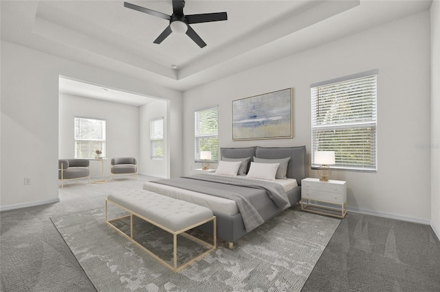 bedroom with ceiling fan, a tray ceiling, and carpet flooring