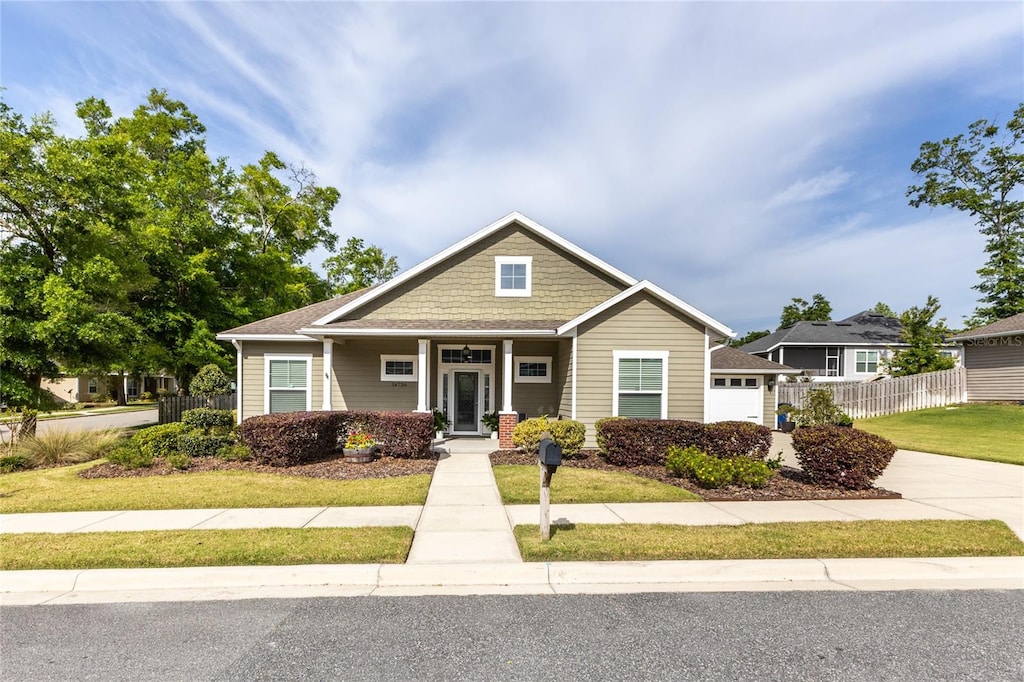 view of front of property with a garage, a front lawn, and covered porch