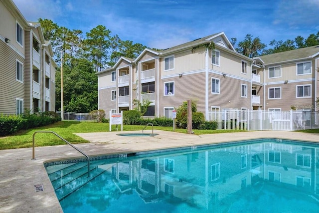 view of swimming pool featuring a community hot tub and a lawn