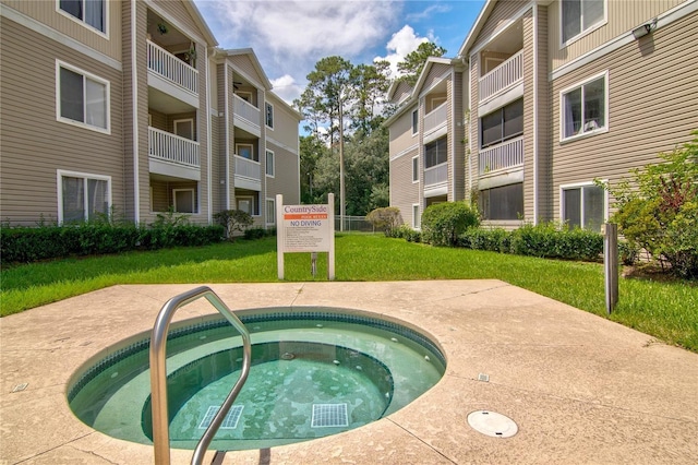 view of swimming pool featuring a community hot tub and a lawn