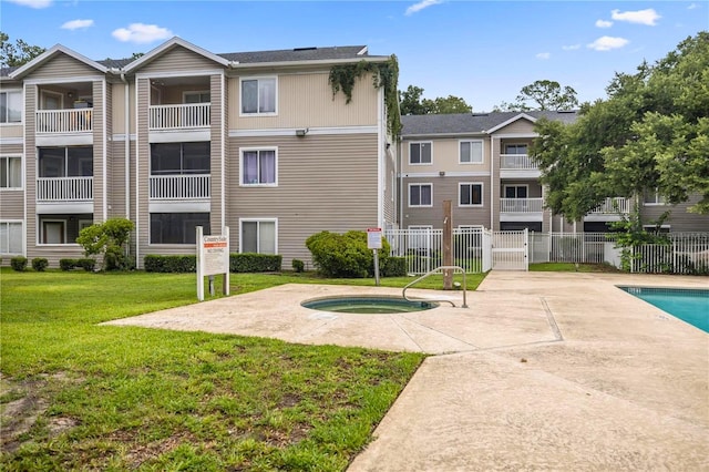 view of home's community featuring a swimming pool with hot tub, a patio area, and a lawn