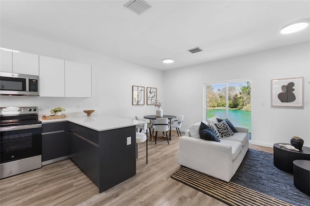 kitchen with stainless steel appliances, light countertops, visible vents, white cabinetry, and a peninsula