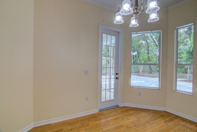 doorway to outside featuring light wood-type flooring, crown molding, and a chandelier