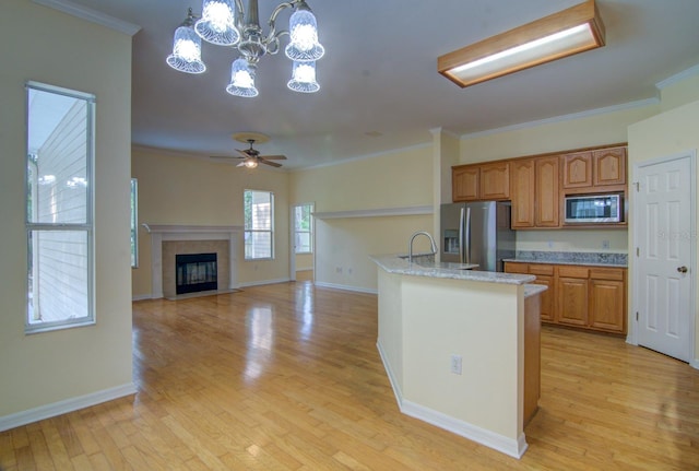 kitchen featuring appliances with stainless steel finishes, hanging light fixtures, crown molding, and light hardwood / wood-style flooring