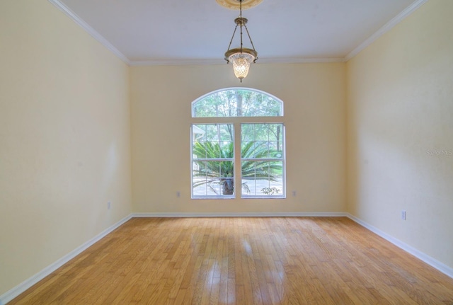 empty room with light wood-type flooring, ornamental molding, and an inviting chandelier