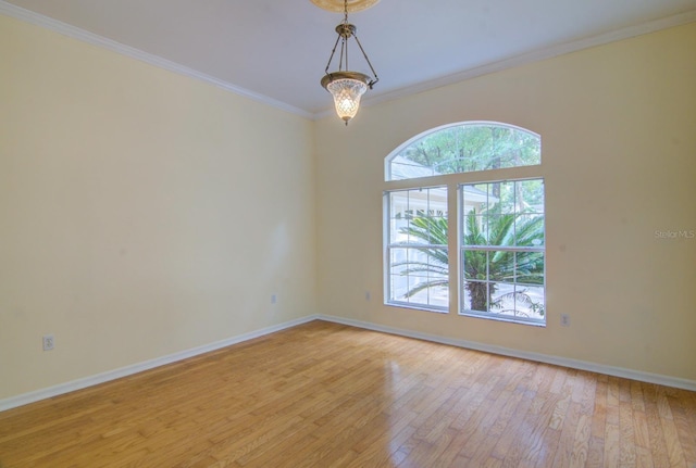 empty room with light hardwood / wood-style flooring, a chandelier, and ornamental molding