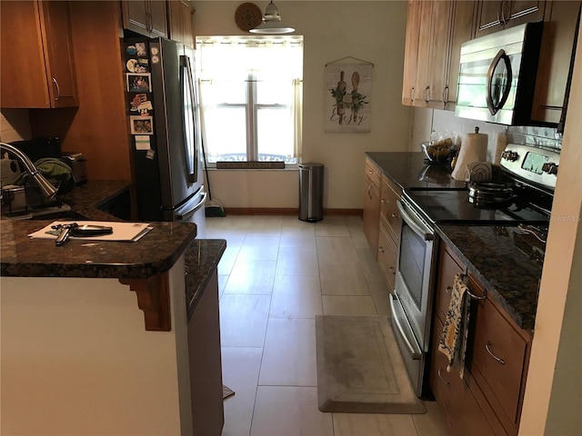 kitchen featuring decorative backsplash, kitchen peninsula, pendant lighting, light tile patterned floors, and stainless steel appliances