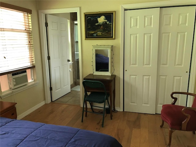 bedroom with cooling unit, a closet, and light hardwood / wood-style floors