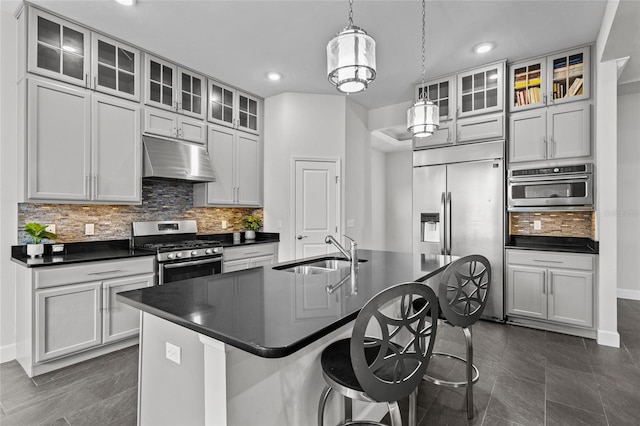 kitchen with stainless steel appliances, hanging light fixtures, sink, and a kitchen island with sink