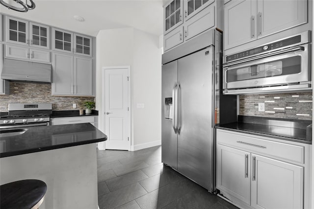 kitchen with decorative backsplash, white cabinets, stainless steel appliances, and dark tile patterned flooring