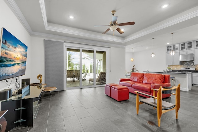 living room with ornamental molding, a tray ceiling, and ceiling fan