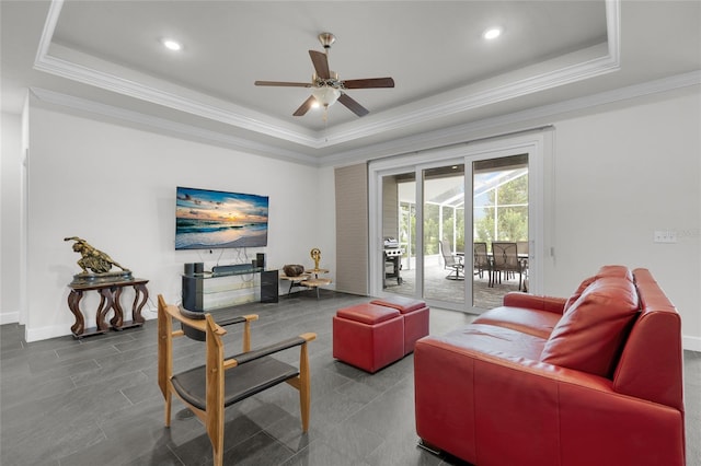 living room featuring ceiling fan, a raised ceiling, and ornamental molding