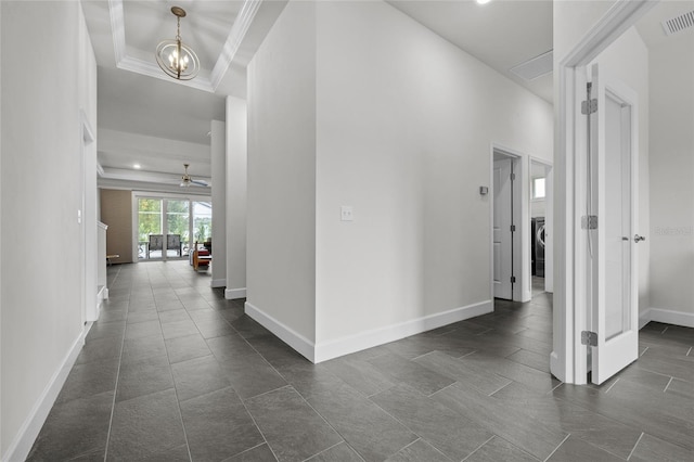 corridor with crown molding, a notable chandelier, and washer / clothes dryer