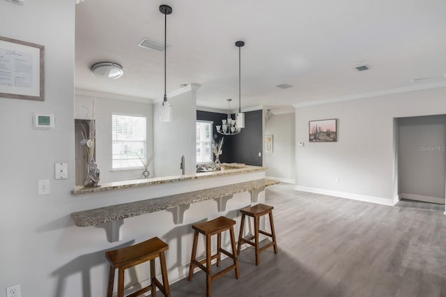 kitchen featuring hardwood / wood-style flooring, crown molding, a notable chandelier, and decorative light fixtures