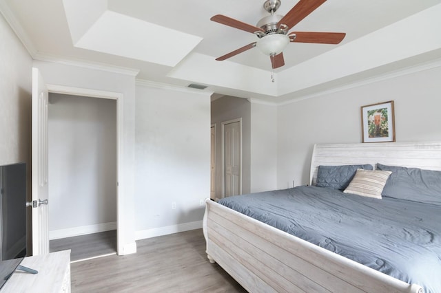 bedroom featuring crown molding, a tray ceiling, hardwood / wood-style floors, and ceiling fan