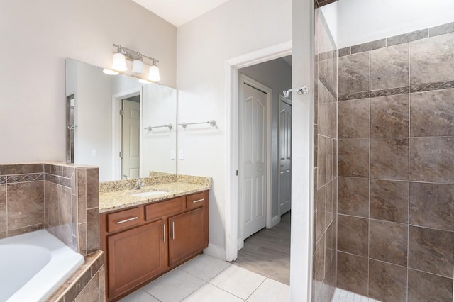 bathroom featuring a relaxing tiled tub, vanity, and hardwood / wood-style floors