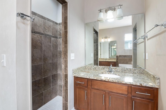 bathroom with a tile shower and vanity