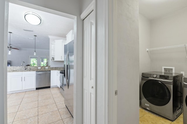 laundry area featuring washing machine and clothes dryer, ceiling fan, light tile patterned floors, and sink