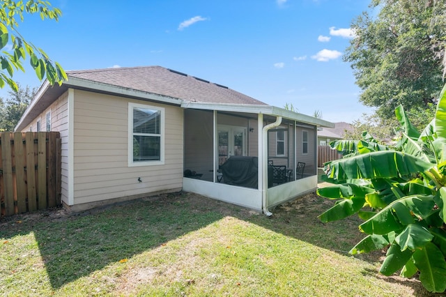 rear view of house featuring a sunroom and a lawn