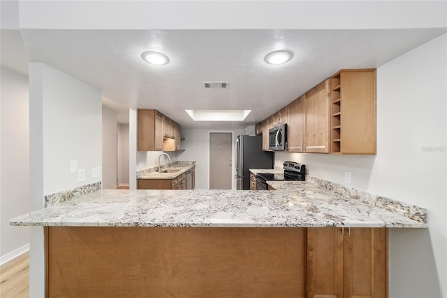 kitchen with light wood-type flooring, kitchen peninsula, sink, and stainless steel appliances