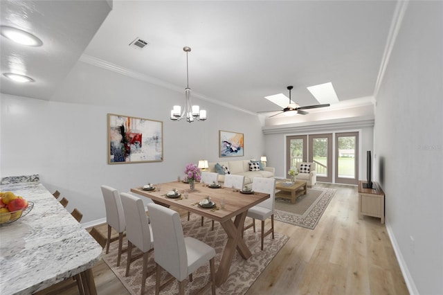 dining space with french doors, light wood-type flooring, a skylight, and ornamental molding