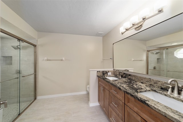 bathroom with a shower with shower door, vanity, toilet, and tile patterned floors