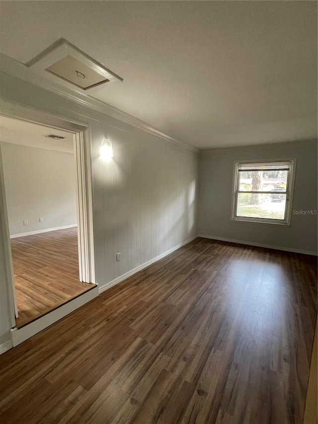 spare room featuring dark wood-type flooring and ornamental molding