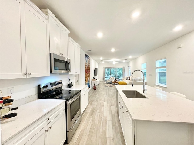 kitchen featuring white cabinetry, sink, an island with sink, and appliances with stainless steel finishes