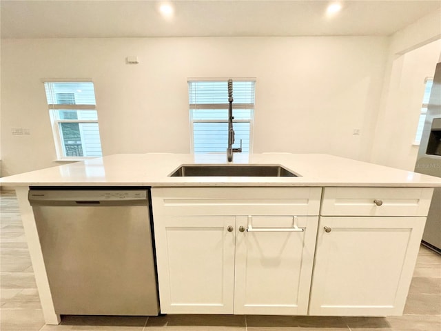 kitchen with dishwasher, a kitchen island with sink, sink, and white cabinets