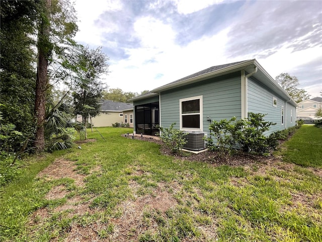 back of house featuring a sunroom, central AC unit, and a lawn