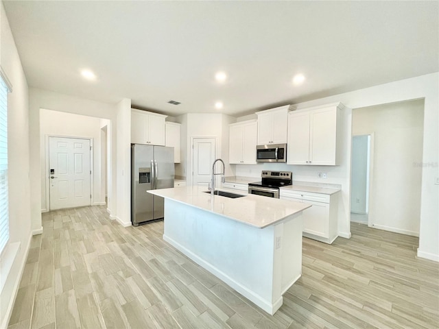 kitchen featuring white cabinetry, appliances with stainless steel finishes, sink, and a kitchen island with sink