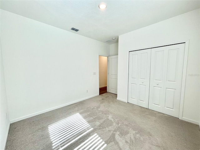 unfurnished bedroom featuring light colored carpet and a closet