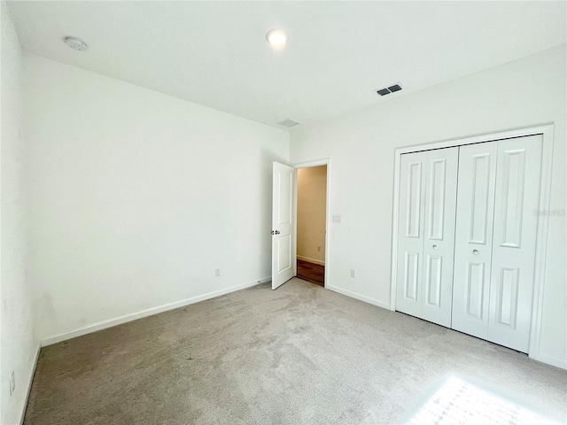 unfurnished bedroom featuring light colored carpet and a closet