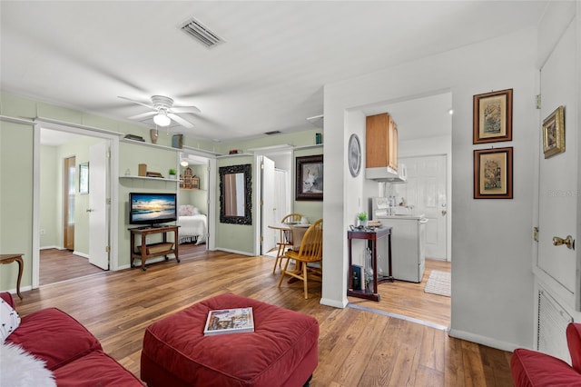 living room with ceiling fan, light hardwood / wood-style flooring, and washer / dryer