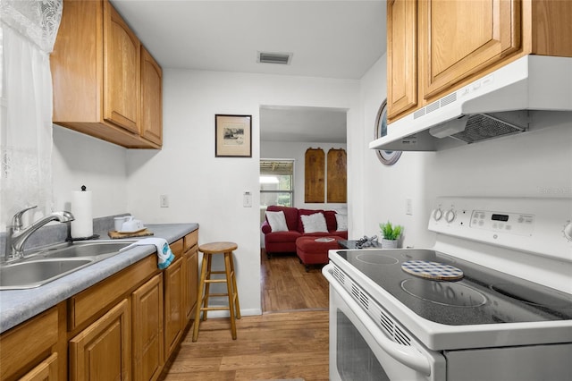 kitchen featuring white electric range, light wood-type flooring, and sink