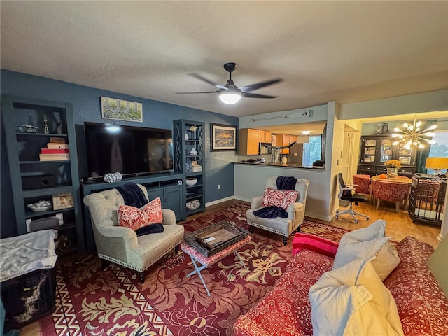 living room featuring ceiling fan with notable chandelier and a textured ceiling