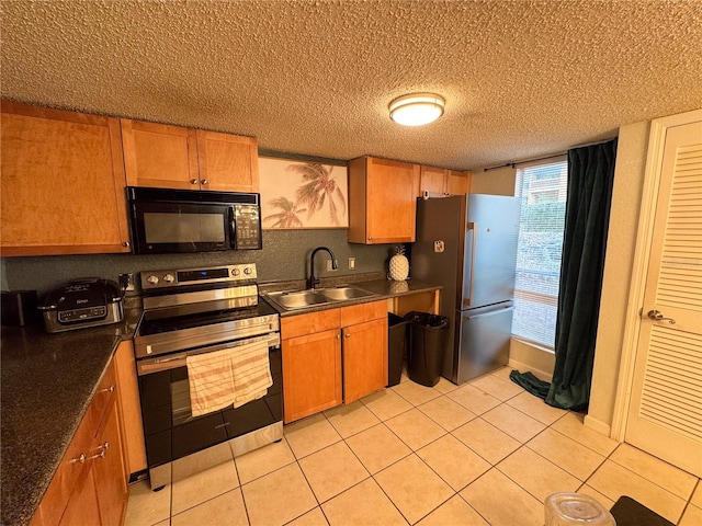 kitchen featuring light tile patterned floors, a textured ceiling, appliances with stainless steel finishes, and sink