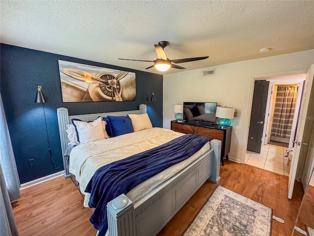 bedroom with wood-type flooring, a textured ceiling, and ceiling fan