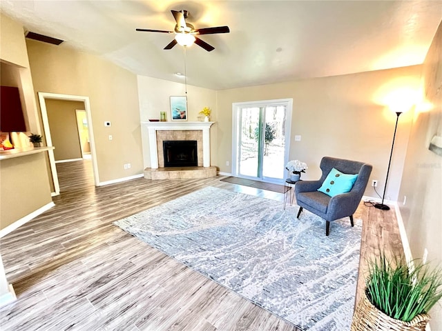 living room featuring hardwood / wood-style flooring, ceiling fan, vaulted ceiling, and a fireplace