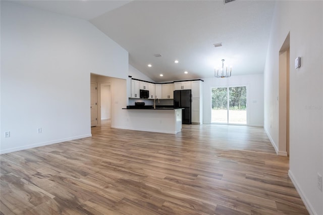 unfurnished living room featuring a chandelier, high vaulted ceiling, sink, and light wood-type flooring