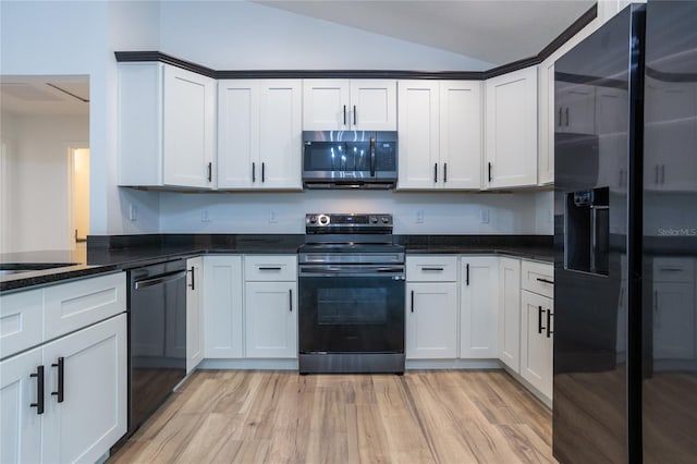 kitchen featuring lofted ceiling, dark stone counters, white cabinetry, black appliances, and light wood-type flooring