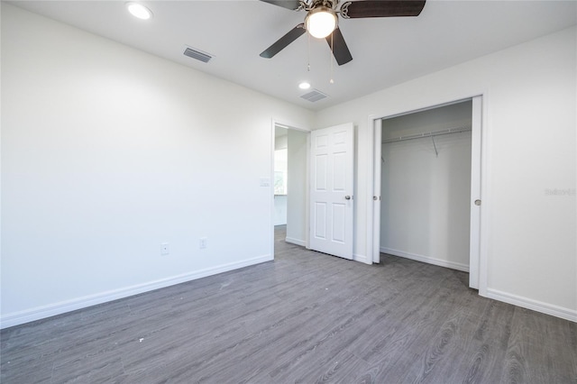 unfurnished bedroom with a closet, visible vents, baseboards, and wood finished floors