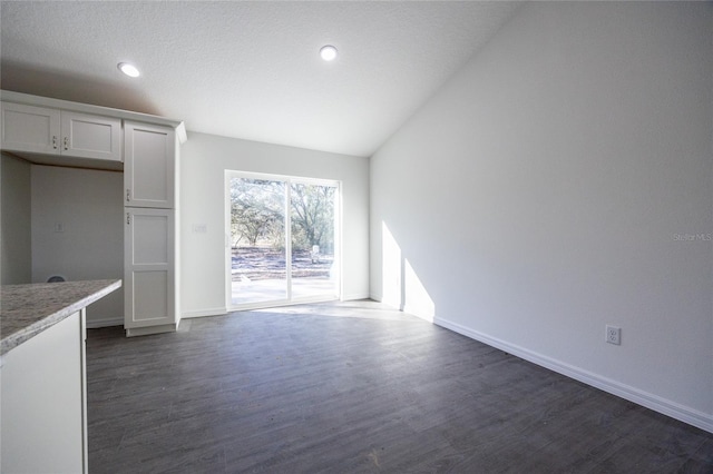 interior space with dark wood-style floors, lofted ceiling, baseboards, and recessed lighting