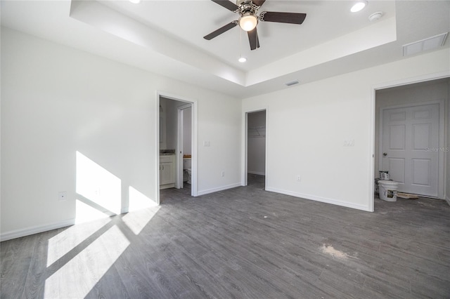 unfurnished bedroom with recessed lighting, dark wood-type flooring, visible vents, baseboards, and a raised ceiling