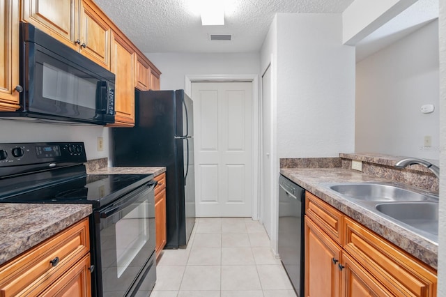 kitchen with a sink, light tile patterned floors, black appliances, visible vents, and a textured ceiling