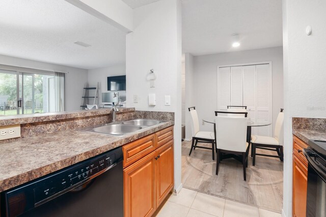 kitchen featuring brown cabinets, a sink, light tile patterned flooring, black dishwasher, and stove